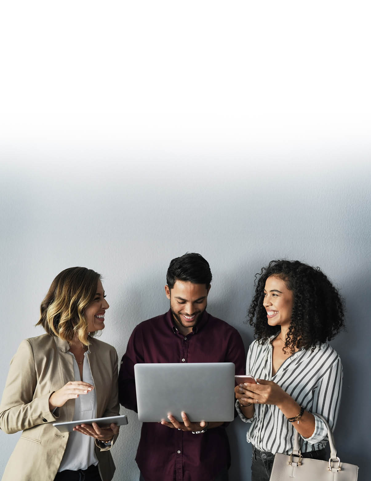 Cropped shot of three young businesspeople talking while using technology against a gray background in the studio